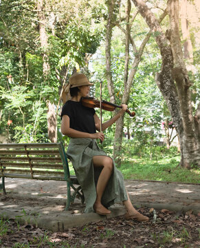Woman wearing woven hat,playing violin for relax time