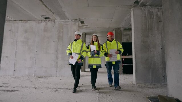 three building inspectors are examining building under construction, architects and female engineer