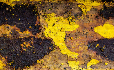 Abstract rusty metal texture in aged yellow paint closeup