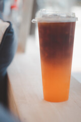 A glass of iced americano black coffee mix with orange juice showing a layer.