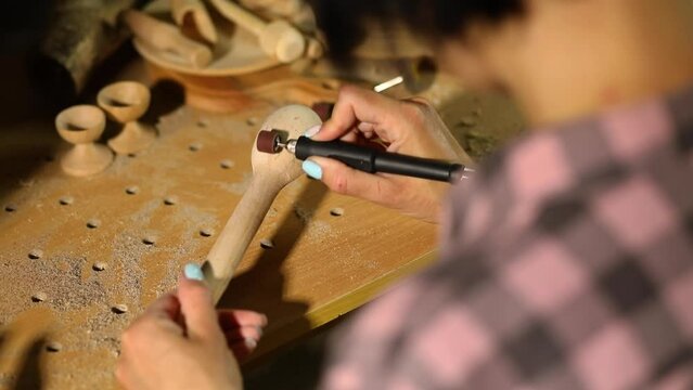 Female using power wood working tools graver for wooden utensils spoon