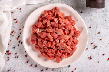 Cubed meat. Red meat in a chopped plate on a stone floor. Butcher products. close up. Top view