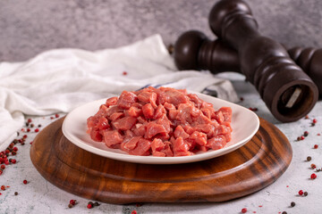 Cubed meat. Red meat in a chopped plate on a stone floor. Butcher products. close up
