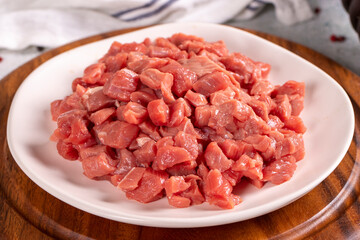 Cubed meat. Red meat in a chopped plate on a stone floor. Butcher products. close up