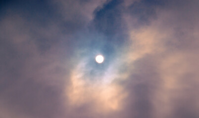 Sun breaking through the clouds with a patch of blue sky