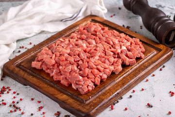 Cubed meat. Chopped red meat in a wooden serving dish on a stone background. Butcher products. close up