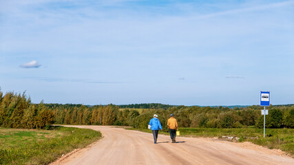 Rural road. A man and a woman walk against the background of endless expanses