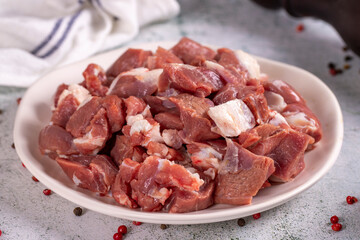 Lamb cubed meat. Chopped red meat in a plate on a stone floor. Butcher products. close up