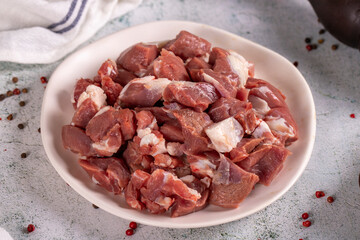 Lamb cubed meat. Chopped red meat in a plate on a stone floor. Butcher products. close up