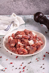 Lamb cubed meat. Chopped red meat in a plate on a stone floor. Butcher products. close up
