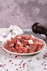 Lamb cubed meat. Chopped red meat in a plate on a stone floor. Butcher products. close up