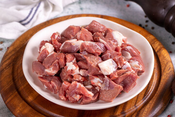 Lamb cubed meat. Chopped red meat in a plate on a stone floor. Butcher products. close up