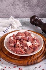 Lamb cubed meat. Chopped red meat in a plate on a stone floor. Butcher products. close up