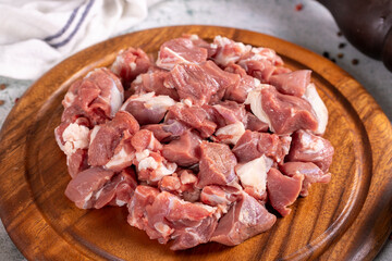 Lamb cubed meat. Chopped red meat in a wooden serving dish on a stone background. Butcher products....