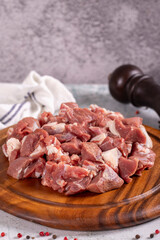 Lamb cubed meat. Chopped red meat in a wooden serving dish on a stone background. Butcher products. close up