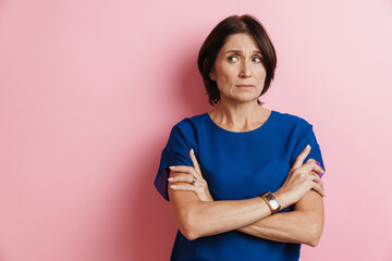 Obraz premium Mature woman frowning while posing with arms crossed