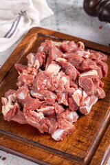 Lamb cubed meat. Chopped red meat in a wooden serving dish on a stone background. Butcher products. close up