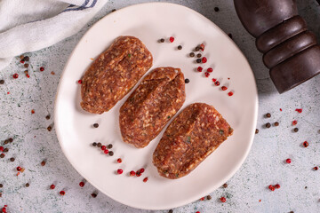 Uncooked spicy grilled meatballs. Meatballs in a plate on a stone background. close up