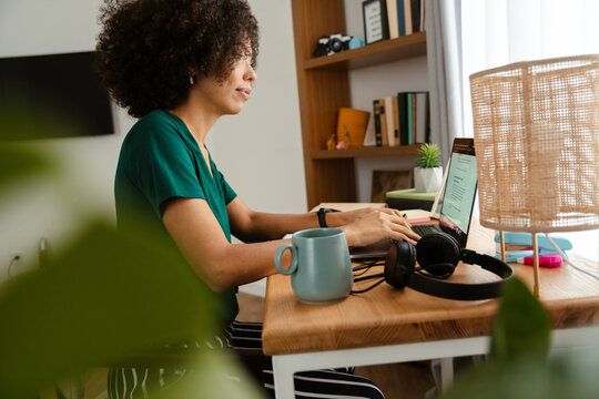 African american young woman sitting at desk and using laptop at home