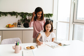 Multiracial sisters smiling while doing homework together