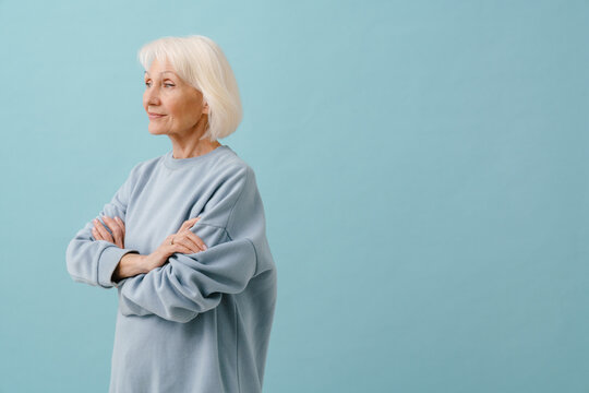 Beautiful senior woman in blue pullover standing with folded arms
