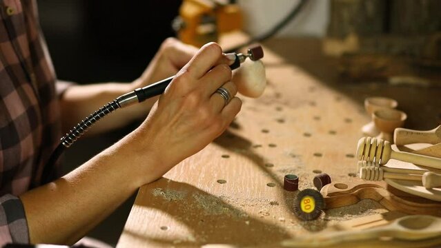 Female using power wood working tools graver for wooden utensils spoon