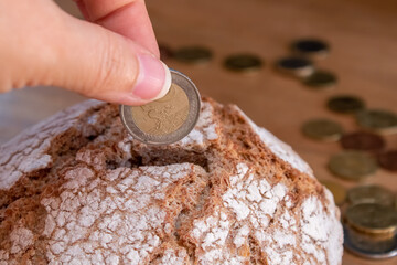 The hand puts the euro coin in the bread like in a money box. Economy, investment in food. food...