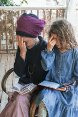 Young religious jewish woman with a headscarf on her head prays with siddur on her knees. Her...