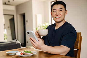Aduld smiling man with phone and cup of tea