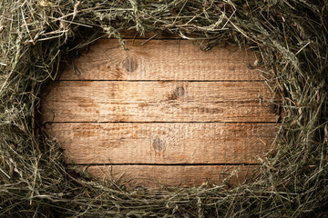 Frame from dry straw hay on vintage wooden board. Rural village background © Ivan Kmit