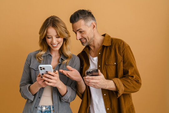 White happy woman and man smiling while using cellphones