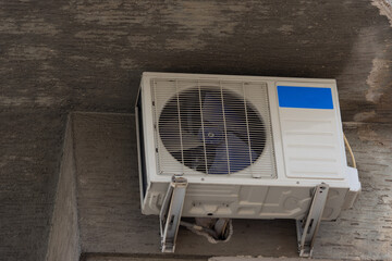 Air conditioner unit installed outside on the wall of an old building