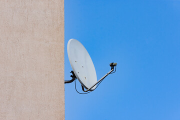 Dish antenna installed on a construction wall against clear blue sky - 519382632
