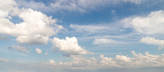 Beautiful panorama or wide angle sky replacement background with layers of fluffy white cumulus clouds balanced well on a blue sky background.