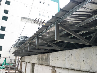 Naklejka premium SELANGOR, MALAYSIA -JUNE 16, 2021: Construction workers install trusses and roofing sheets at construction sites. Lightweight roof trusses used are more economical, sturdy and fast.