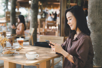 At a coffee shop, a woman happily smiles while using her smartphone to play social media.
