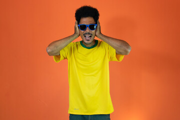 Black man football fan. Man in yellow shirt isolated on orange background.