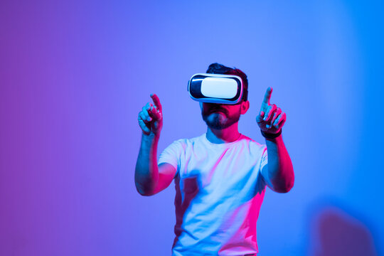 Picture of young man wearing virtual reality headset and playing a videogame online. Future technology.