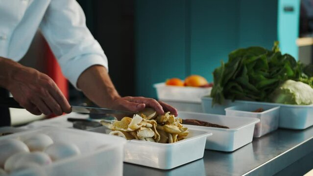 Professional kitchen, close-up: The chef cuts mushrooms, prepares a delicious dish in the restaurant