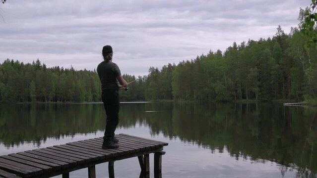 Man fishing from a wooden pier on a Lake in Finland in summer