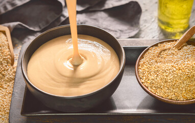 Arabic Cuisine; Pouring tasty Tahini Sauce onto black bowl.