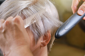 Professional hairdresser drying hair with a  hair straightener client. Shallow depth of field