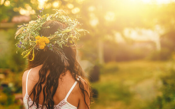 Woman in flower wreath on sunny meadow, Floral crown, symbol of summer solstice.