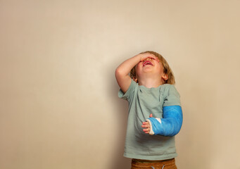 Crying boy with broken hand stand over wall - obrazy, fototapety, plakaty