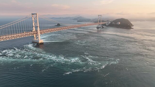Aerial fly in towards whirlpools and suspension bridge at sunset