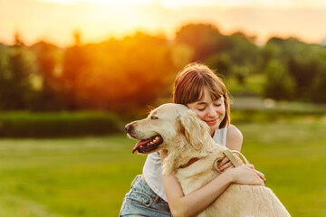 Portrait of teenage girl petting golden retriever outside in sunset