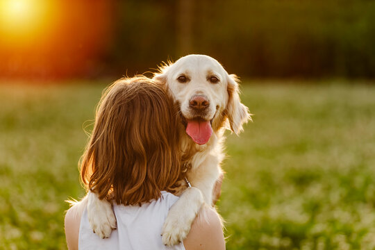 Portrait of teenage girl petting golden retriever outside in sunset - Powered by Adobe