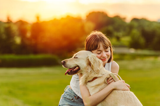Portrait of teenage girl petting golden retriever outside in sunset - Powered by Adobe