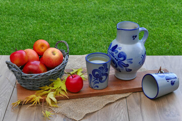 Traditioneller deutscher Apfelwein aus Hessen. Wein in einem blauen Krug vor einem Korb mit Äpfeln.