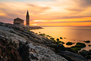 The city of Caorle in Italy at sunrise and its landmark on the main promenade, the Santuario della...